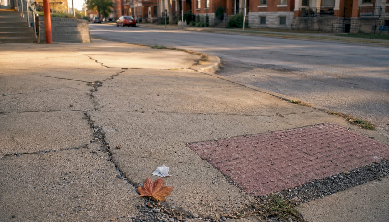Close-up of sidewalk cracks and curb ramp