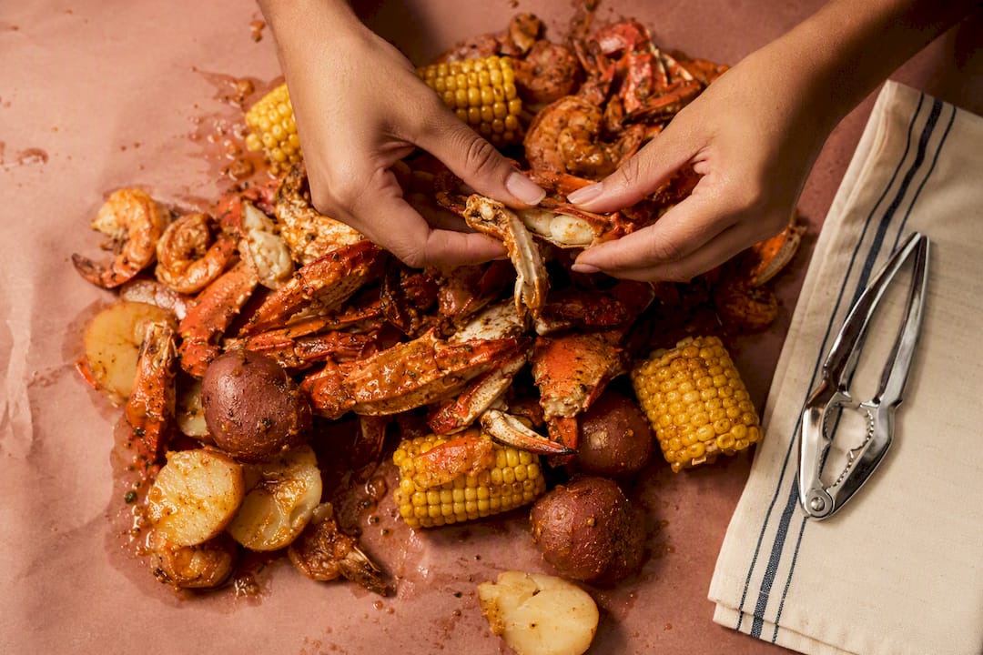 Hands opening crab at a seafood boil